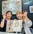 　人々の多様性を妖怪になぞらえて描き、自ら解説した著書の原画展会場で、来場者と記念撮影する東ちづるさん（右）＝２０２５年９月、東京都多摩市
