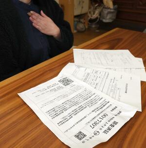 罹災(りさい)証明書の交付に先立つ被害調査が終わったことを示す書類を並べる会社員女性=新潟市西区