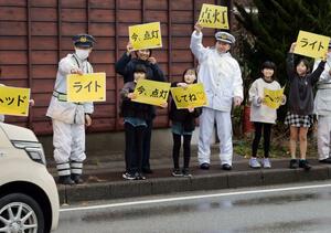 早めのライト点灯を呼びかける児童と大人たち=佐渡市畑野