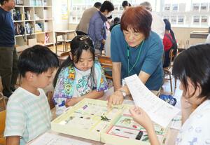 薬物標本について説明する保護司会のメンバーと、標本をじっくりと眺める子どもたち=南魚沼市浦佐
