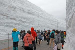 　「立山黒部アルペンルート」が全線開通し、「雪の大谷ウオーク」を楽しむ観光客＝１５日午前、富山県立山町