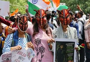 ゴキブリを模したお面をかぶった抗議集会の参加者=20日、インド・ニューデリー(共同)