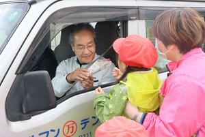 ドライバーにサツマイモを手渡す柏崎二葉幼稚園の年長児=柏崎署前