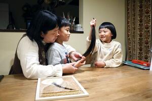 切った髪を見つめる(右から)中倉縁さん、弟の慶ちゃん、母親の亜矢子さん=胎内市