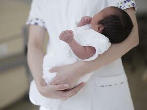 　病院で助産師に抱かれる新生児