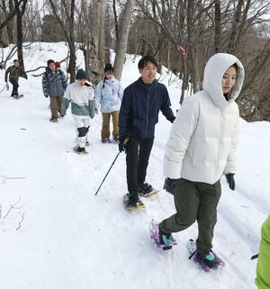 スノーシューを履いて林の中を歩く参加者＝１１日、長岡市宮本東方町