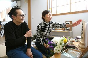 笠原平治さんの位牌に手を伸ばす長田孝宏さん、正子さん夫妻。大好きだった父に毎日話し掛ける=燕市