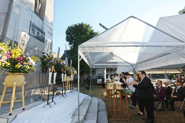 戦災殉難者慰霊塔の前で手を合わせる市民ら＝１日午前６時半ごろ、長岡市表町１