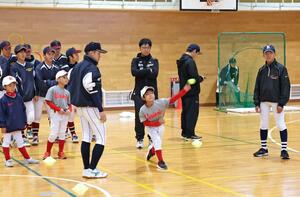 中高生が見守る中、ボールを投げる学童チームの選手＝柏崎市元城町１