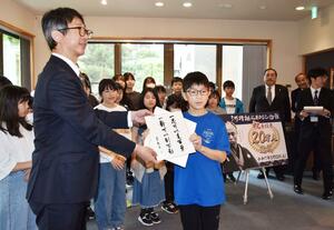 20万人達成の記念セレモニー。阪之上小の児童代表が記念品を受け取った=長岡市長町1