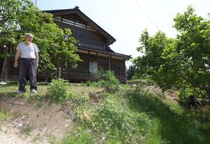 敷地全体が盛り上がり、段差となった隆起の被害を語る男性=6月、石川県珠洲市