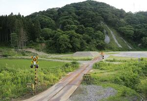 豪雨被災から8月で3年となるJR米坂線の踏切。線路には雑草がうっそうと生い茂っている=関川村土沢付近