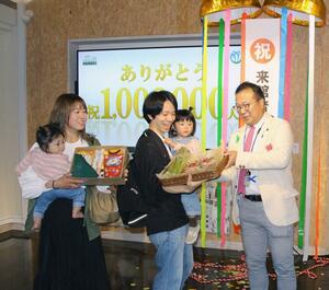 100万人目の来館を祝うセレモニーで、田辺正幸市長(右)から記念が贈られた金子裕司さん家族=五泉市赤海