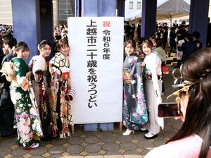 「二十歳を祝うつどい」で再会した友人らと喜び合い記念撮影する参加者=6日、上越市下門前