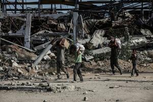 　２１日、イスラエル軍が攻勢をかけるガザ中部で、配給物資を運ぶ人たち（ゲッティ＝共同）