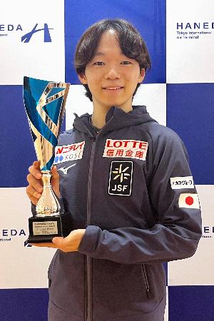 トロフィーを手に撮影に応じるフィギュアスケート男子の鍵山優真=16日、羽田空港