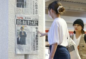 安倍晋三元首相が銃撃を受け、死去したことを伝える新潟日報の号外を見る人=2022年7月8日、新潟市中央区