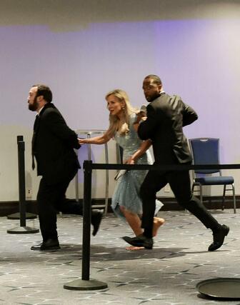 ２５日、ホワイトハウス記者会主催の夕食会会場で発砲音がした後、逃げる参加者＝ワシントン（ロイター＝共同）