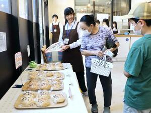 新たに開発したオリジナルのパンを紹介する高田商業高校の生徒=8月1日、上越市本町4