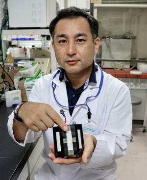 開発した「遠紫外線」の装置を持つ徳島大の馬渡一諭講師=7月、徳島市