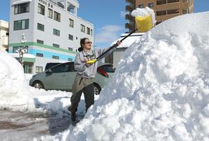 降り積もった自宅前の雪をスコップで積み上げる住民=2月22日午後2時30分過ぎ、長岡市神田町1