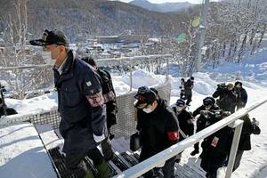　エスカレーター事故の現場（右奥）前を通り、スキー場施設の家宅捜索に入る捜査員＝６日午前１０時４分、北海道小樽市