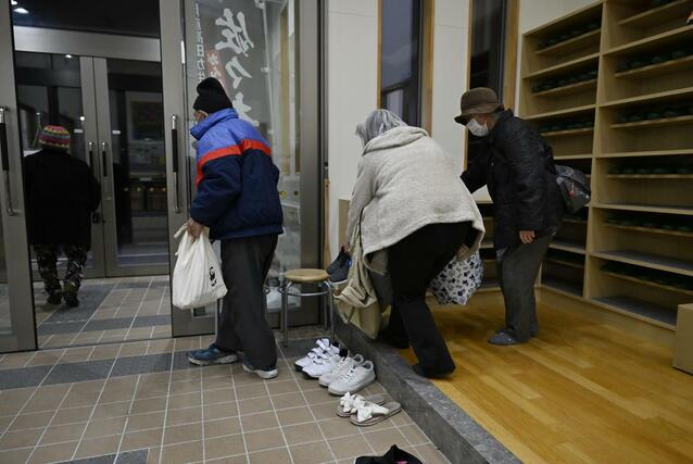 津波警報が注意報となり、避難所を出る人たち＝９日午前３時すぎ、岩手県陸前高田市