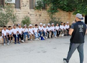 ヨルダン川西岸ファラのサマーキャンプで指導員のかけ声に合わせてあいさつをする子どもたち=7月30日(共同)