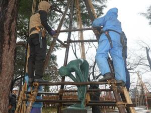 ブロンズ像の冬囲いを外す公園の管理人ら=6日、上越市の高田城址公園