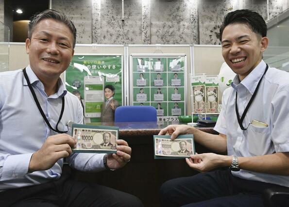 埼玉りそな銀行の窓口で受け取った新紙幣を手にする人たち＝７月３日午前、さいたま市