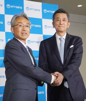 握手を交わす、NTTデータグループの佐々木裕社長(左)とNTTデータの鈴木正範社長=26日午後、東京都江東区