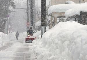 上越市高田で積雪が1メートルを超え、除雪機で道路の排雪に追われる市民=10日、同市大町4