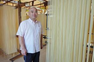 自社工場で乾燥中のそうめんと森和也さん=徳島県つるぎ町
