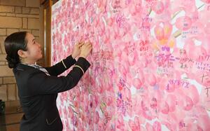 夢が書かれた桜の用紙を貼るスタッフ=3月24日、湯沢町湯沢