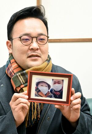 病院で撮影した祖母との写真を手にする神喰雄太さん。祖母が着用していたマフラーを現在も愛用している=糸魚川市