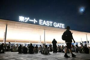 大阪メトロ中央線が運転見合わせとなり、万博会場で座り込む人たち=13日午後11時2分、大阪市此花区の夢洲