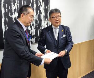 寄付の目録を手渡す角谷正雄理事長(右)=柏崎市役所