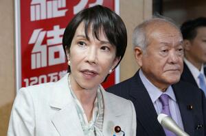 自民党本部で記者団の取材に応じる高市総裁。右は鈴木幹事長=7日午後、東京・永田町