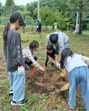 子どもたちが苗木を植え、シャベルや手で土をかけた植樹体験=佐渡市城腰