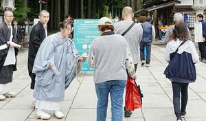 高野山の金剛峯寺の奥之院入り口で、肩や足の露出が多い服装を控えるよう啓発する僧侶ら=6日午前、和歌山県高野町