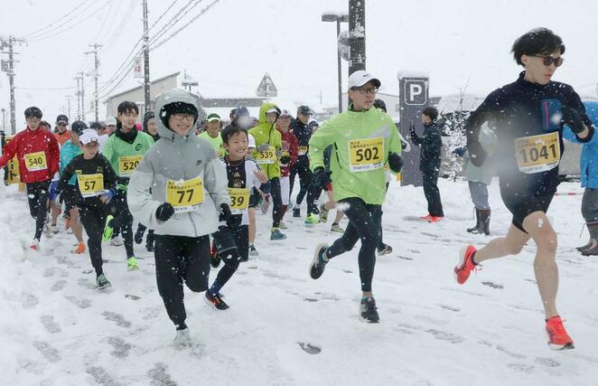 路面が雪で覆われた悪条件の中、勢いよくスタートするランナー＝１月１日、三条市