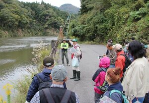 荷揚げ港として栄えた川港跡を見学するフカボリウオークの参加者=阿賀町日出谷