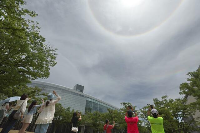 「日暈（ひがさ）」を撮影する観光客ら＝１８日、新潟市中央区