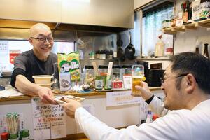 熱々の焼き鳥を提供する店主の森山章さん（左）。風呂上がりの一杯に、常連客も思わず笑顔＝新潟市江南区亀田新明町２