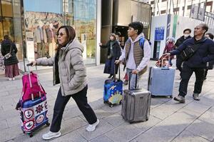 東京・銀座でスーツケースを手に歩く外国人ら=1月17日午後