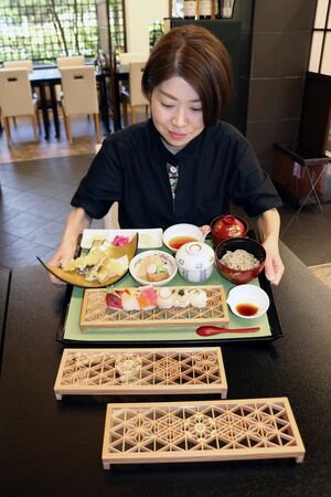 組子細工のプレートに寿司を盛り付けた「組子 上てまり寿司膳」を紹介する「日本料理きふね」若おかみの佐藤梢さん。彩りや味付けにもこだわった=加茂市穀町