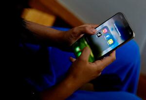 交流サイトのアプリが表示されたスマートフォンを操作する高校生=11月、オーストラリア・メルボルン(ロイター=共同)