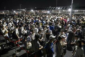 　大阪メトロ中央線が運転見合わせとなり、タクシー待ちで西ゲート前に並ぶ大勢の人たち＝１３日、大阪市此花区の夢洲