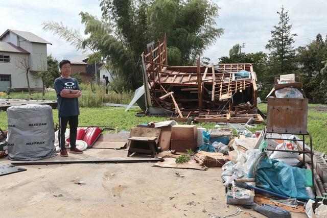突風で吹き飛んだ車庫（男性が立っている場所に元々車庫があった）＝１１日、上越市三和区井ノ口