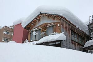 雁木に積もった雪を下ろす市民＝２５日、長岡市弓町２